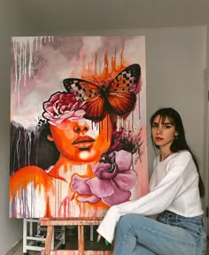 a woman sitting in front of a painting with butterflies on her face and flowers around her head