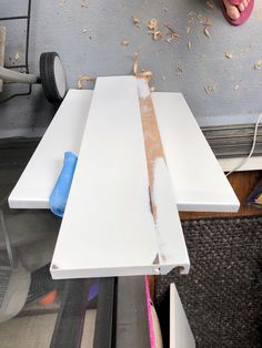 a person is working on some white boards with wood shavings and glue in front of them