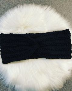 a black knitted headband laying on top of a white fur rug