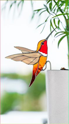 a glass hummingbird sitting on top of a plant