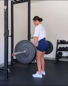 a woman lifting a barbell in a gym