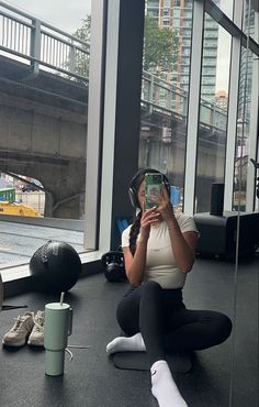 a woman sitting on the floor taking a selfie with her cell phone and headphones