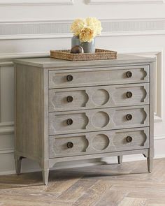 a gray dresser with drawers and flowers on top