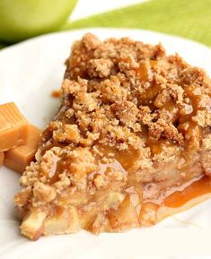 a slice of apple pie on a plate with caramel slices and an apple in the background