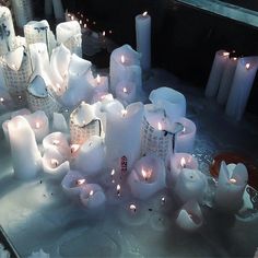 many white candles are lit on a table