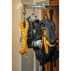 a backpack hanging from a hook on a door way with rope and water bottle in it