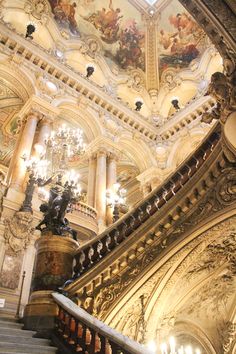 an ornate staircase with chandeliers and paintings on the ceiling