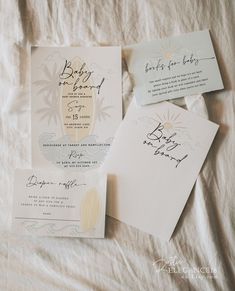 wedding stationery on top of a bed with white sheets