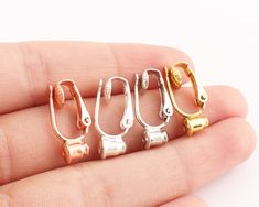 four pairs of gold, silver and rose gold nose rings on a person's finger