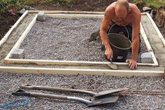 a man kneeling down in front of a cement slab with tools on the ground next to it