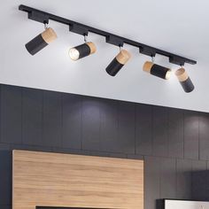 three lights are hanging from the ceiling above a fireplace in a living room with black walls and wood paneling