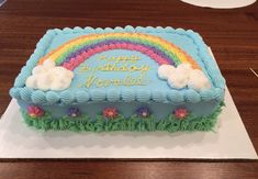 a birthday cake decorated with rainbows and clouds