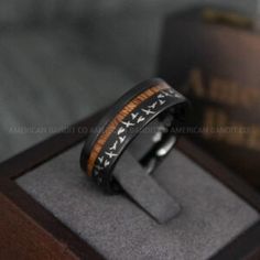 a ring with an arrow pattern on it sitting in a wooden box next to a book