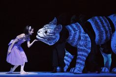 a woman in a purple dress standing next to two stuffed animals with their mouths open