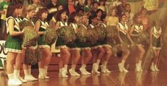 a group of cheerleaders standing in front of a crowd with their skirts down