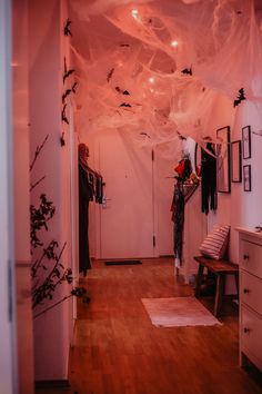 a hallway decorated for halloween with bats and spider webs hanging from the ceiling above