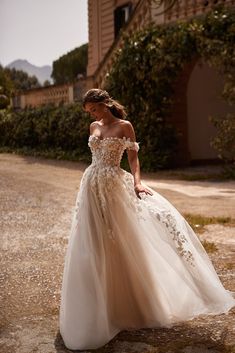 a woman in a wedding dress standing on the side of a road with her hand on her hip