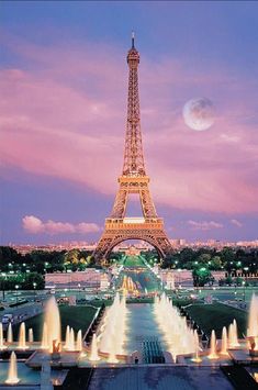 the eiffel tower is lit up at night in paris, france with water fountains