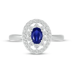 This unforgettable ring dazzles with an oval-cut blue lab-created sapphire at the center. An oval frame of white lab-created sapphires forms a sophisticated and sparkling silhouette. The ring is crafted in sterling silver with a rhodium finish. Blue Oval Diamond Halo Ring, Oval Blue Diamond Halo Ring, Oval Blue Cubic Zirconia Sapphire Ring, Blue Oval Lab-created Sapphire Diamond Ring, Oval Blue Lab-created Sapphire Diamond Ring, Oval Sapphire Ring In Diamond White, Oval Blue Sapphire Ring With Diamond Accents, Elegant Sapphire Oval Halo Ring, Elegant Oval Sapphire Halo Ring