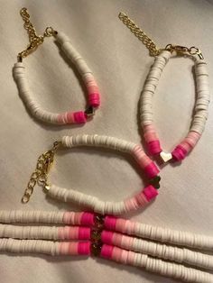 three necklaces made out of white and pink beads with gold chains on the sides