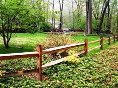 a wooden fence surrounded by green grass and trees