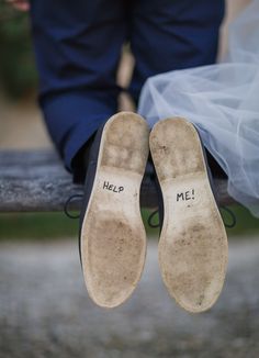 a pair of shoes with words written on them are sitting on a bench next to a bride and groom