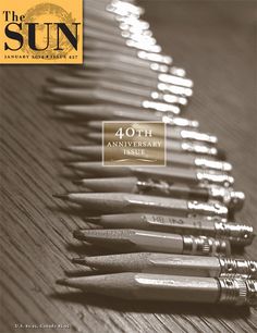 a row of pens sitting next to each other on top of a wooden table in front of the sun logo