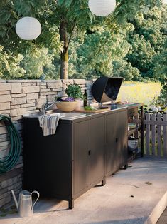 an outdoor kitchen on a patio with lights hanging from the ceiling