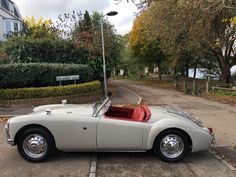 an old white sports car parked on the street