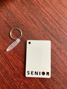 a keychain with the word senior on it sitting next to a small white tag