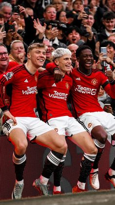 three men in red and white soccer uniforms are posing for a photo with their arms around each other