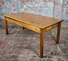 a wooden table sitting on top of a carpeted floor next to a brick wall