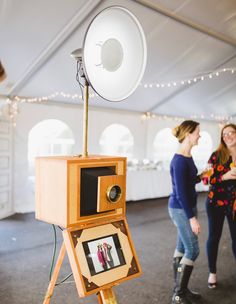 two women standing next to an old fashioned camera