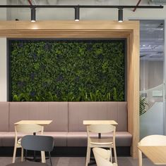 a green wall in the middle of a restaurant with two tables and chairs around it