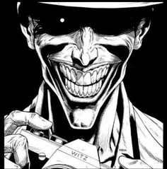 the joker is holding a camera in his right hand and wearing a fedora hat