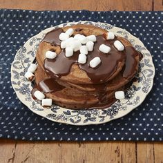 a chocolate cake with marshmallows on top sitting on a blue and white plate