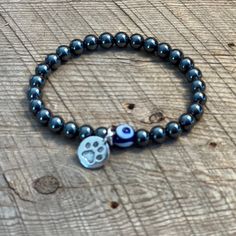 SariBlue Hematite and Evil Eye Bracelet with Pewter Paw Print Charm These bracelets bring you good luck and positive grounding energy. The hematite stones have a strong grounding ability that helps to clear and calm your mind.  The small handmade Turkish evil eye bead adds good luck and protection.  This subtle and simple bracelet is perfect for any animal lover.  *Listing is for one bracelet. *Due to the nature of handmade materials, exact beads, color and shape may vary in the item you receive Hematite Stretch Bracelet As Gift, Silver Hypoallergenic Stretch Bracelet For Healing, Silver Hypoallergenic Stretch Bracelet, Magnetic Hematite Beaded Bracelets Gift, Silver Hematite Jewelry For Healing, Healing Hematite Silver Jewelry, Silver Hematite Beaded Bracelets For Healing, Silver Hematite Stretch Bracelet Spiritual, Silver Hematite Spiritual Stretch Bracelet