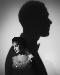 a woman standing in front of a wall with her shadow on the wall