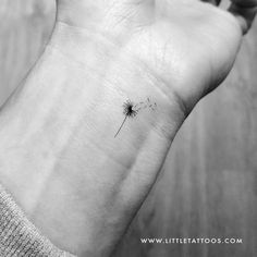 a black and white photo of a dandelion on someone's left wrist