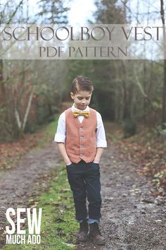 a young boy wearing a vest and bow tie standing on a dirt road in the woods