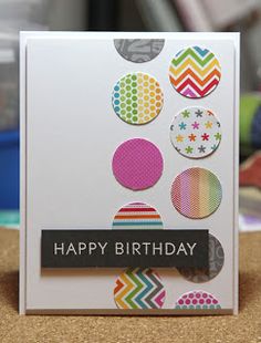 a happy birthday card with colorful circles and dots on the front, sitting on a table