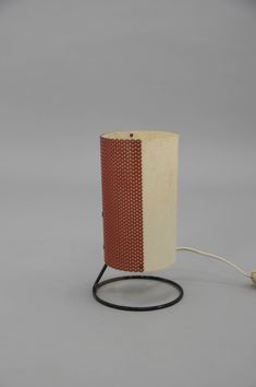 a lamp that is sitting on top of a wooden stand with a cord attached to it