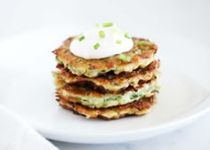 a stack of pancakes topped with sour cream and chives on top of a white plate