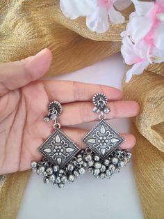 Jazz up your ethnic look with these gungroo earrings. This Ghungroo Silver Oxidised Earrings are handcrafted with oxidized silver and feature an iconic bunch of playful ghungroos that add a lively character to your look. With ghungroos always being a trendsetter, these earrings will surely be a favorite! Silver Dual-tone Danglers, Festive Oxidized Metal Danglers, Festive Metal Danglers With Oxidized Finish, Oxidized Metal Chandbali Chandelier Earrings, Metal Chandbali Chandelier Earrings With Oxidized Finish, Bohemian Chandbalis With Oxidized Finish, Festive Silver Chandelier Earrings With Oxidized Finish, Silver Oxidized Chandbali Danglers, Silver Oxidized Chandbali Drop Earrings