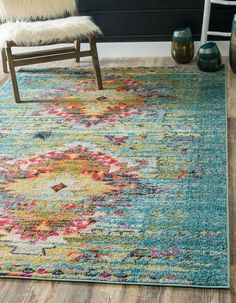 an area rug with colorful flowers on it and a chair in the corner next to it