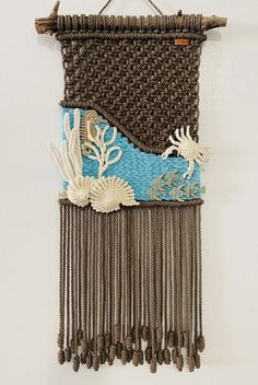 a wall hanging made out of woven material with shells and seaweeds on it