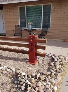 a red mailbox sitting in front of a house next to a gravel covered yard