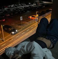 a person laying on the ground in front of a parking lot with lots of parked cars