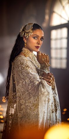 a woman in a white dress with gold jewelry on her head and arms around her neck