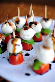 small appetizers with toothpicks and tomatoes on a white plate